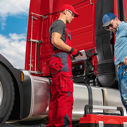 Mechanics inspecting red semi truck